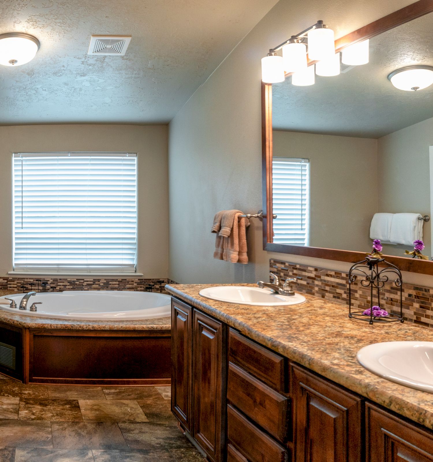 A clean, modern bathroom featuring a double sink vanity with a large mirror, a bathtub, and beige walls.