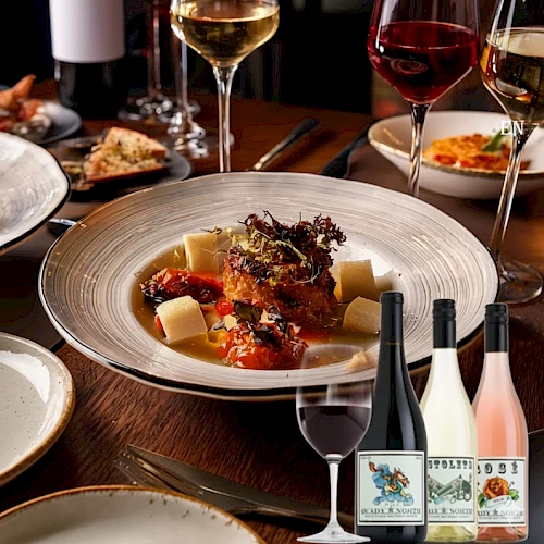 A fine dining scene with a plated main dish, several wine glasses, and bottles on a table, suggesting a sophisticated dinner with wine pairings.